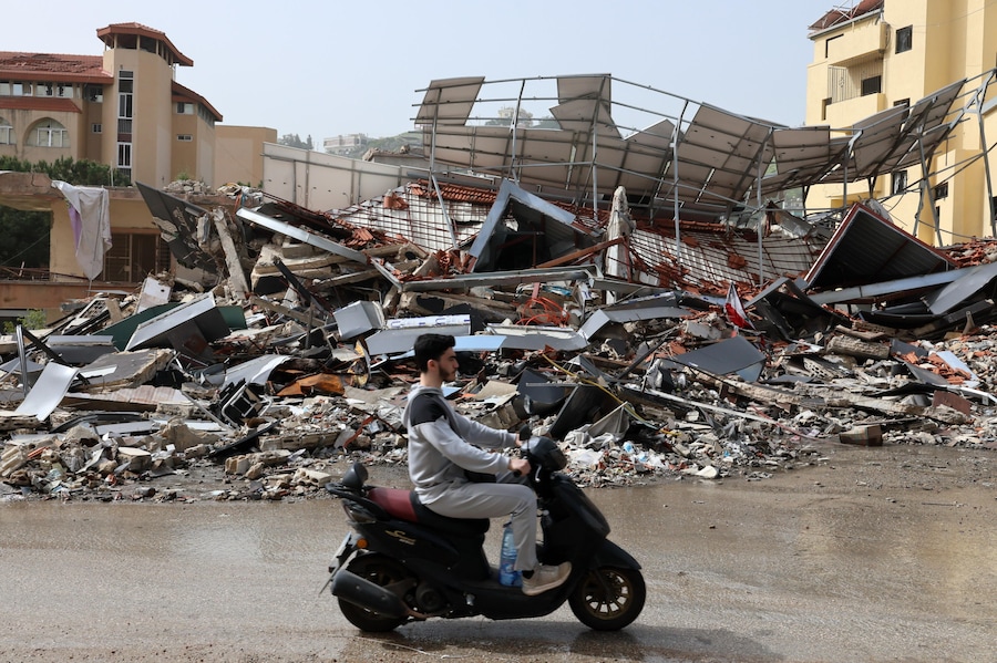Un uomo sullo scooter passa accanto a un edificio distrutto nella città di Nabatieh, nel sud del Libano, il 18 aprile 2026. (EPA)