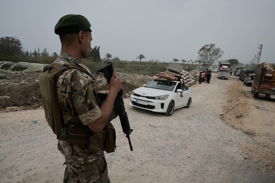 Un soldato libanese monta la guardia mentre gli sfollati attraversano un ponte distrutto per tornare ai propri villaggi a Qasmiyeh, nei pressi della città di Tiro, sabato 18 aprile 2026. (AP)