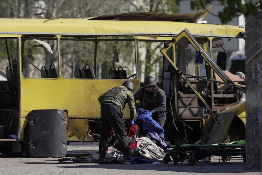 Uomini in tenuta protettiva recuperano il corpo di un residente rimasto ucciso all'interno di un autobus comunale durante un attacco con droni russi nella città di Nikopol, nella regione di Dnipropetrovsk. (REUTERS/Stringer)