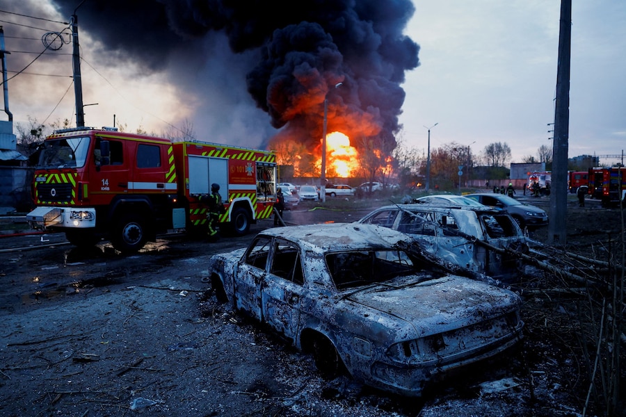 I vigili del fuoco sono al lavoro accanto a veicoli distrutti, sul luogo di un attacco missilistico russo, a Kiev. (REUTERS/Valentyn Ogirenko)