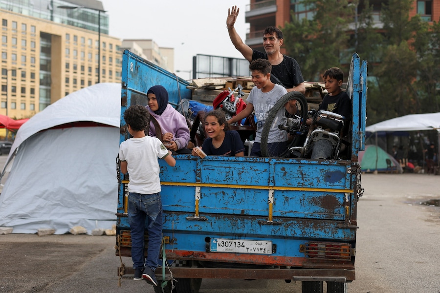 Una famiglia sfollata saluta i propri parenti mentre torna alla propria casa nella periferia sud di Beirut a bordo di un camion carico dei propri averi, in un accampamento di fortuna allestito durante il cessate il fuoco tra Libano e Israele, a Beirut, in Libano. (REUTERS/Saleh Salem)