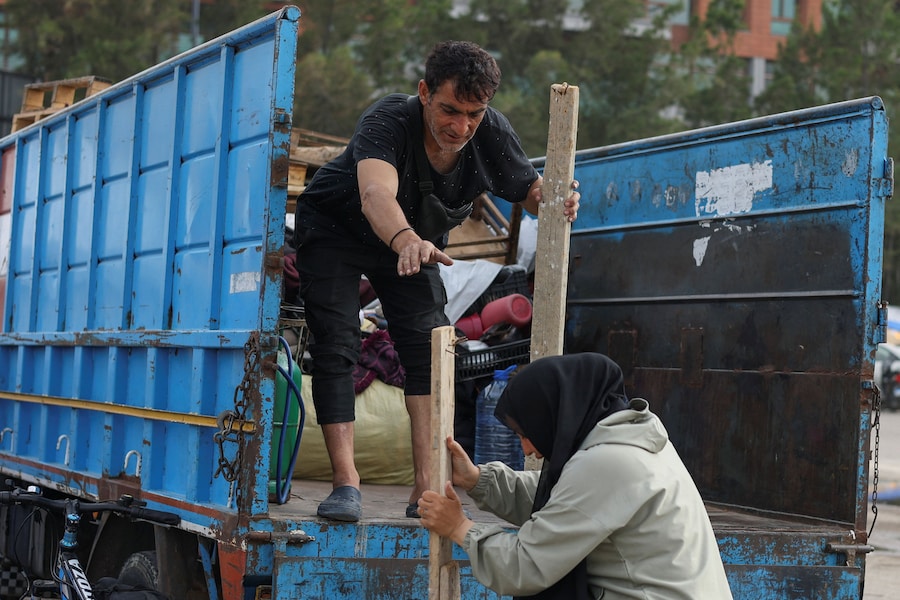 Una coppia sfollata carica i propri effetti personali su un camion mentre si prepara a tornare alla propria casa nella periferia sud di Beirut, in Libano. (REUTERS/Saleh Salem)