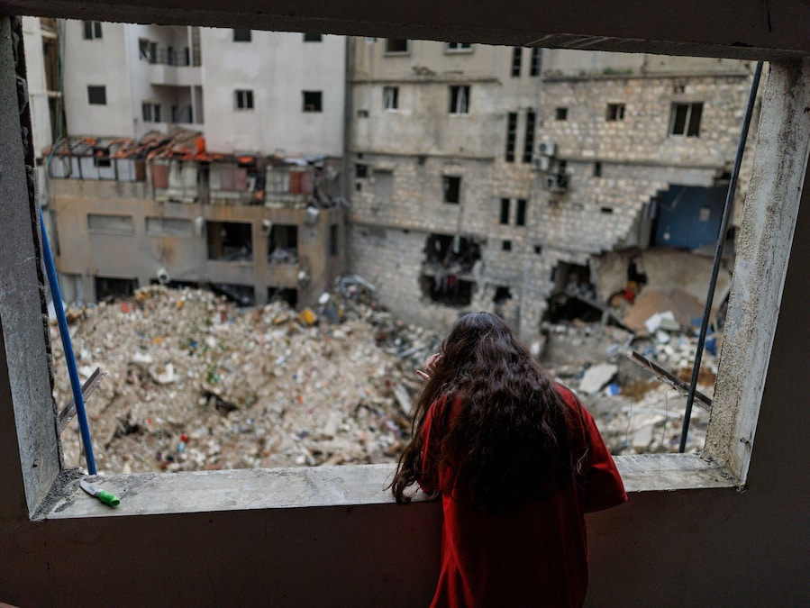 Alaa Dahnoun, 12 anni, che ha raccontato di essere sopravvissuta a un attacco israeliano che l’ha costretta a fuggire con i genitori a Beirut, guarda fuori dalla finestra danneggiata del suo appartamento dopo essere tornata a casa in seguito all’entrata in vigore di una tregua di 10 giorni tra Libano e Israele, a Nabatieh, in Libano. (REUTERS/Zohra Bensemra)