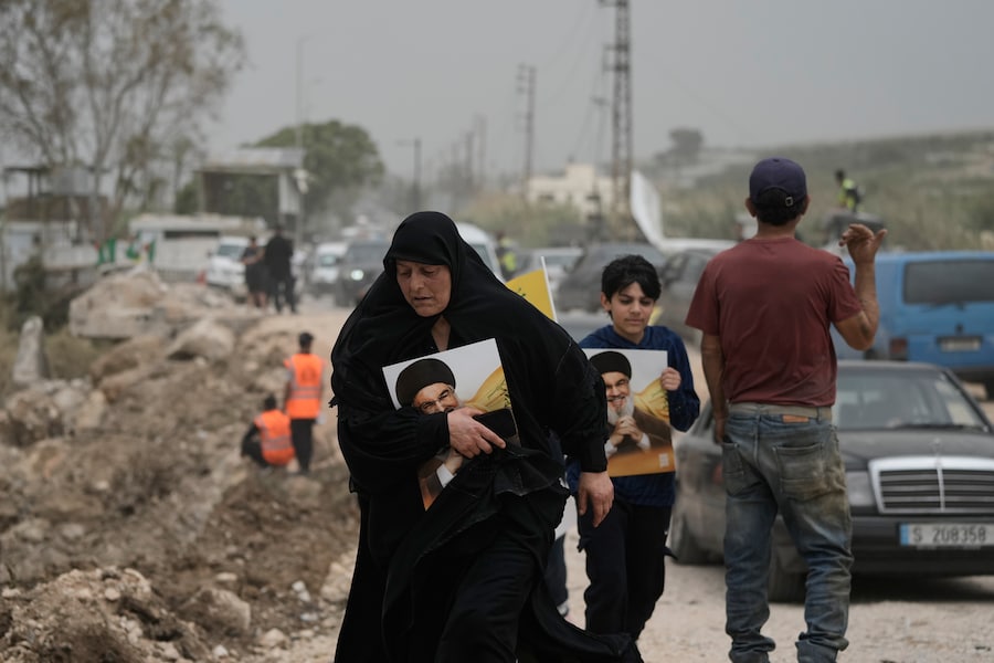 A Qasmiyeh, nei pressi della città di Tiro, nel Libano meridionale, alcuni sfollati, mentre attraversano a piedi un ponte distrutto per tornare ai propri villaggi, tengono in mano dei ritratti del defunto leader di Hezbollah Sayyed Hassan Nasrallah. (AP Photo/Bilal Hussein/ Associated Press / LaPresse/ APN)