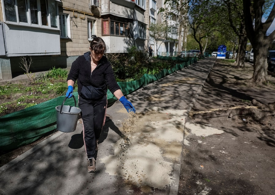 Una dipendente comunale copre le tracce di sangue con della sabbia sul luogo della sparatoria avvenuta ieri a Kiev. (REUTERS/Gleb Garanich)