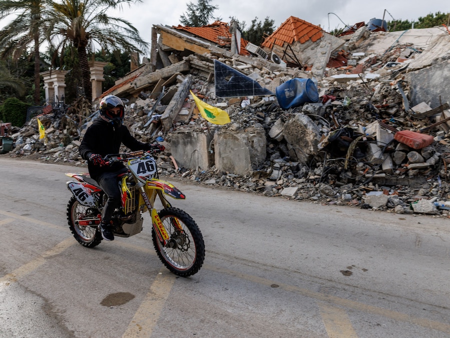 Un uomo passa in moto davanti a un edificio che ospitava abitazioni e un ristorante ed è stato colpito da un attacco israeliano poche ore prima della tregua, nel corso di una tregua di 10 giorni tra Libano e Israele, a Zrarieh, in Libano. (REUTERS/Zohra Bensemra)