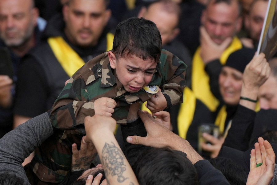 Un bambino in uniforme militare piange mentre viene portato in braccio dai partecipanti al funerale dei combattenti di Hezbollah uccisi durante il conflitto con Israele, prima dell’entrata in vigore del cessate il fuoco di 10 giorni tra Libano e Israele, nella periferia meridionale di Beirut, Libano (REUTERS)