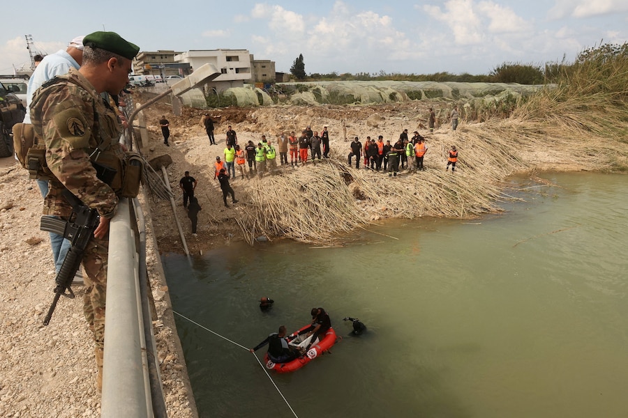 Un membro dell’esercito libanese osserva i soccorritori impegnati nella ricerca di vittime sul luogo di un attacco israeliano a un ponte a Qasmiyeh, nel sud del Libano (REUTERS)