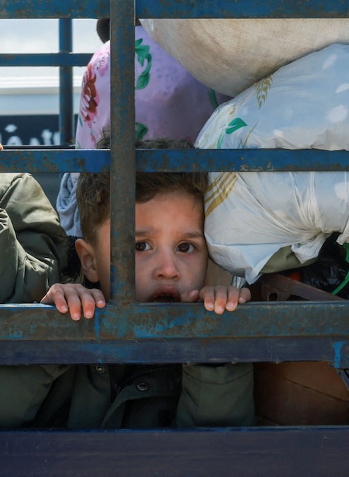 Un bambino sfollato osserva la scena mentre viaggia sul retro di un camion carico di effetti personali, mentre gli sfollati si dirigono verso le loro case nel Libano meridionale, durante un cessate il fuoco di 10 giorni tra Libano e Israele, a Qasmiyeh, nel Libano meridionale (REUTERS)