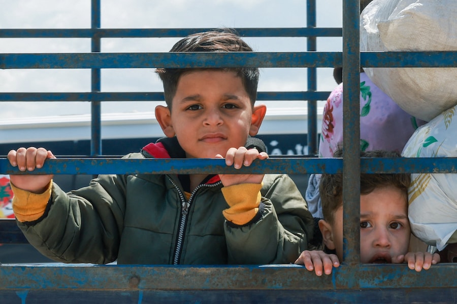 Bambini sfollati osservano mentre viaggiano sul retro di un camion carico di effetti personali diretti verso le loro case nel Libano meridionale, durante un cessate il fuoco di 10 giorni tra Libano e Israele, a Qasmiyeh, nel Libano meridionale (REUTERS)