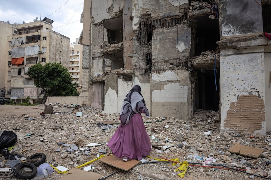 Una donna cammina tra edifici danneggiati durante il cessate il fuoco di 10 giorni tra Libano e Israele, nella periferia meridionale di Beirut, Libano (REUTERS)