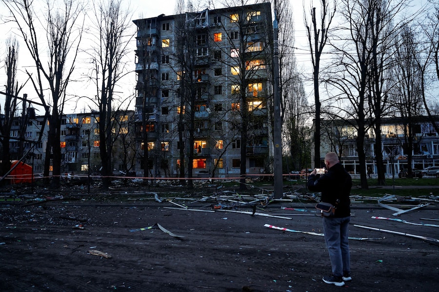 Un uomo riprende la scena con il cellulare nei pressi del luogo colpito da un missile russo, a Kiev. (REUTERS/Valentyn Ogirenko)