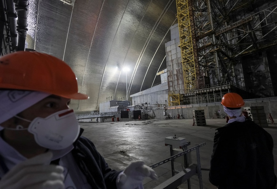 Un visitatore osserva l'area adiacente al vecchio sarcofago che ricopre il quarto reattore danneggiato, sotto la struttura del Nuovo Confinamento di Sicurezza (NSC) presso la centrale nucleare di Cernobyl, mentre è in corso l'attacco della Russia all'Ucraina, nella regione di Kiev. (REUTERS/Gleb Garanich)