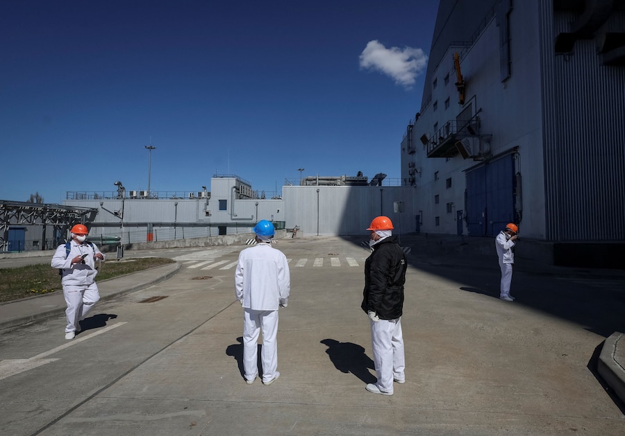 I visitatori si trovano nei pressi della struttura del Nuovo Confinamento di Sicurezza (NSC), che ricopre il vecchio sarcofago che racchiude i resti del quarto reattore danneggiato della centrale nucleare di Cernobyl, mentre la Russia attacca l'Ucraina, nella regione di Kiev. (REUTERS/Gleb Garanich)