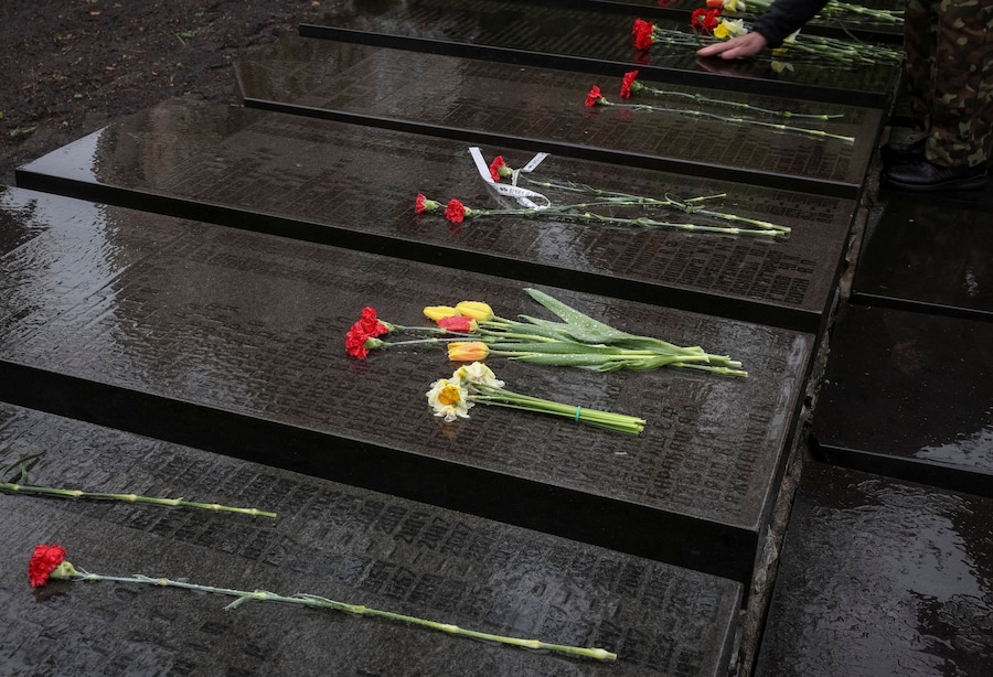 Un visitatore depone dei fiori presso un memoriale dedicato ai vigili del fuoco e agli operai deceduti in seguito all'esplosione di un reattore nella centrale nucleare di Cernobyl, mentre partecipa a una cerimonia commemorativa per il 40° anniversario del disastro di Cernobyl, a Kiev. (REUTERS)