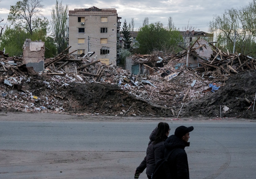 Persone camminano accanto a edifici distrutti, nella città di Sloviansk, nella regione di Donetsk. (REUTERS/Serhii Korovainyi)