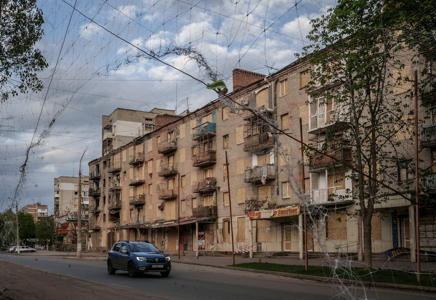 Un'auto passa accanto a un edificio danneggiato, nella città di Sloviansk, nella regione di Donetsk. (REUTERS/Serhii Korovainyi)