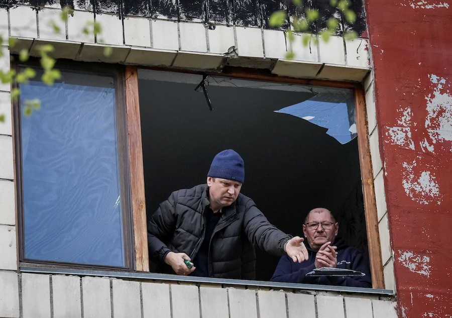 I residenti rimuovono i vetri rotti da una finestra di un condominio danneggiato da un attacco con droni russi, a Kiev. (REUTERS/Gleb Garanich)