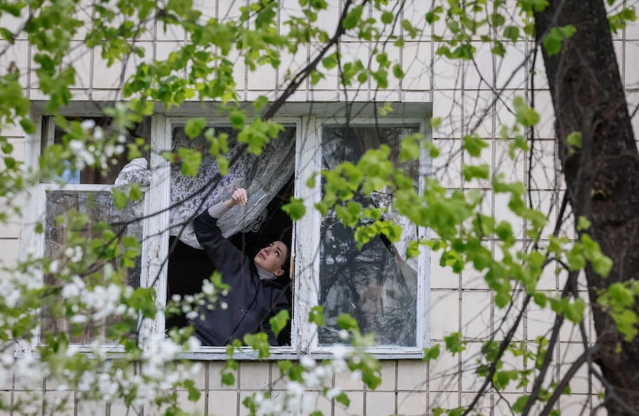 A Kiev, un residente rimuove i vetri rotti da una finestra di un condominio danneggiato da un attacco con droni russi. (REUTERS/Gleb Garanich)