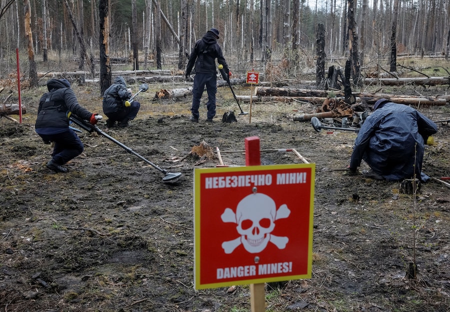 Gli operatori dell'HALO Trust (Hazardous Area Life-support Organization), un'organizzazione umanitaria non governativa che si occupa principalmente dello sminamento e della rimozione di altri ordigni esplosivi, utilizzano metal detector per cercare mine e ordigni inesplosi lasciati sul posto dopo l'occupazione russa della zona, nei pressi del villaggio di Myrotske, nella regione di Kiev. (REUTERS/Gleb Garanich)