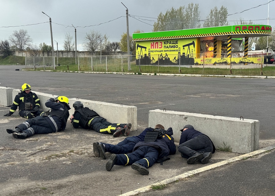 I vigili del fuoco si mettono al riparo temendo un'esplosione mentre operano su una stazione di servizio colpita da un attacco con droni russi. (REUTERS)