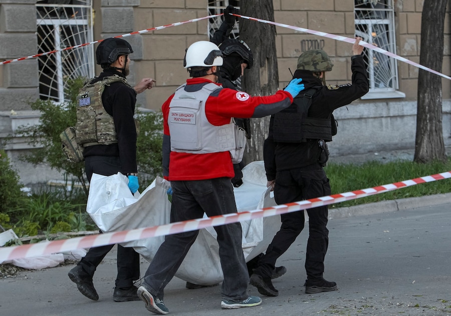 Agenti di polizia e un operatore sanitario trasportano una sacca contenente il corpo di una persona rinvenuta sotto le macerie di un dormitorio gravemente danneggiato durante un attacco missilistico russo, nel contesto dell'offensiva russa contro l'Ucraina, a Dnipro, Ucraina. (REUTERS)