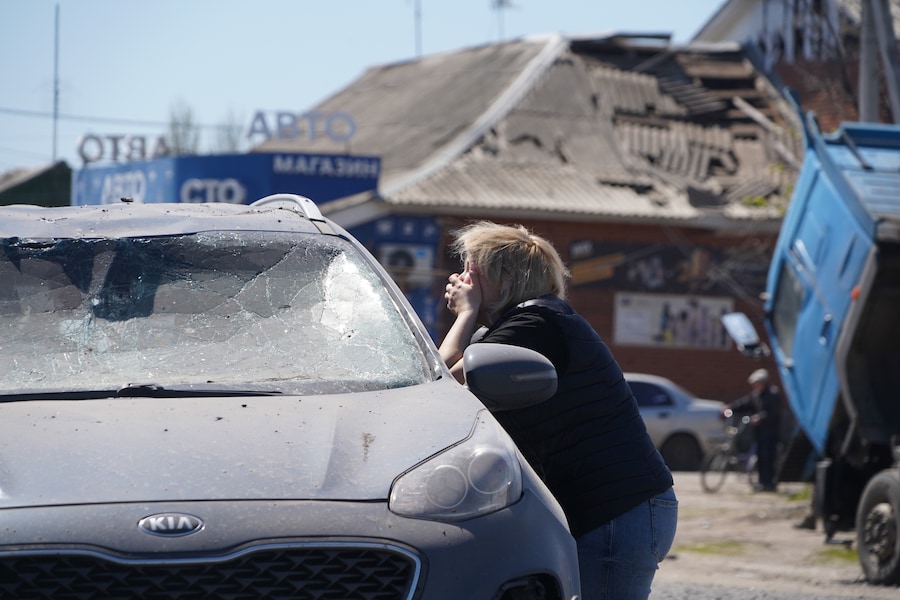 Una donna piange mentre osserva il corpo senza vita di un automobilista all'interno di un'auto danneggiata in seguito a un attacco missilistico russo a Merefa, nella regione di Kharkiv, in Ucraina. (APN)