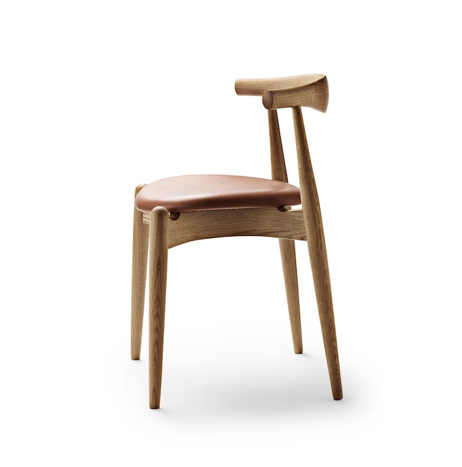 Sedia Elbow, designer Hans J. Wegner 1956, con ampio e solido schienale orizzontale piegato per diventare bracciolo, CARL HANSEN & SØN (1.248 €).