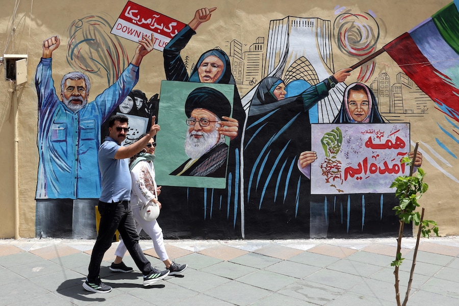 Una coppia iraniana cammina accanto a un murale contro gli Stati Uniti e Israele in una strada di Teheran, Iran, l'8 maggio 2026. L'Iran e gli Stati Uniti si sono scontrati a colpi di arma da fuoco nello Stretto di Hormuz nonostante il cessate il fuoco. EPA/ABEDIN TAHERKENAREH (EPA)