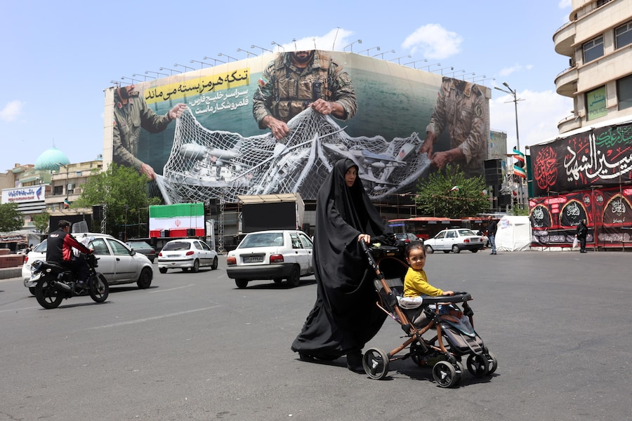 Una donna iraniana cammina accanto a un enorme cartellone pubblicitario anti-statunitense su cui è riportata la frase in persiano «Lo Stretto di Hormuz rimane chiuso» nella piazza Engelab (della Rivoluzione) a Teheran, in Iran, l'8 maggio 2026. L'Iran e gli Stati Uniti si sono scontrati a colpi di arma da fuoco nello Stretto di Hormuz nonostante il cessate il fuoco. EPA/ABEDIN TAHERKENAREH (EPA)