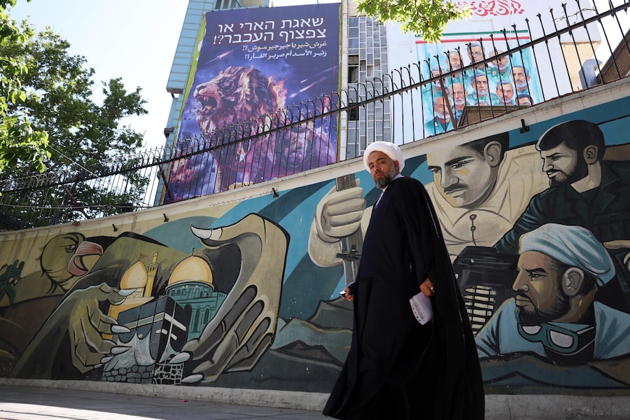 Un religioso cammina accanto a un cartellone pubblicitario contro Israele e gli Stati Uniti su cui è scritto in persiano «Il ruggito di un leone o il piagnucolio di un topo?!», appeso in Piazza Palestina a Teheran, in Iran, l'11 maggio 2026. I (EPA)