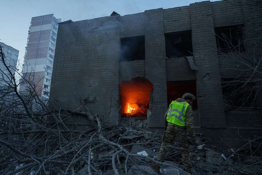 Un agente di polizia osserva un edificio danneggiato in seguito a un attacco russo contro un quartiere residenziale a Kiev. (APN)
