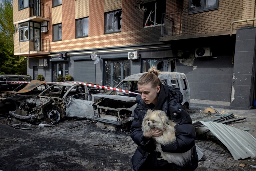 Una residente porta in braccio un cane mentre scappa da un condominio per evitare la caduta di schegge di vetro dopo che l’edificio è stato danneggiato durante una notte di attacchi missilistici e con droni russi a Shchaslyve, nei pressi di Kiev (REUTERS)
