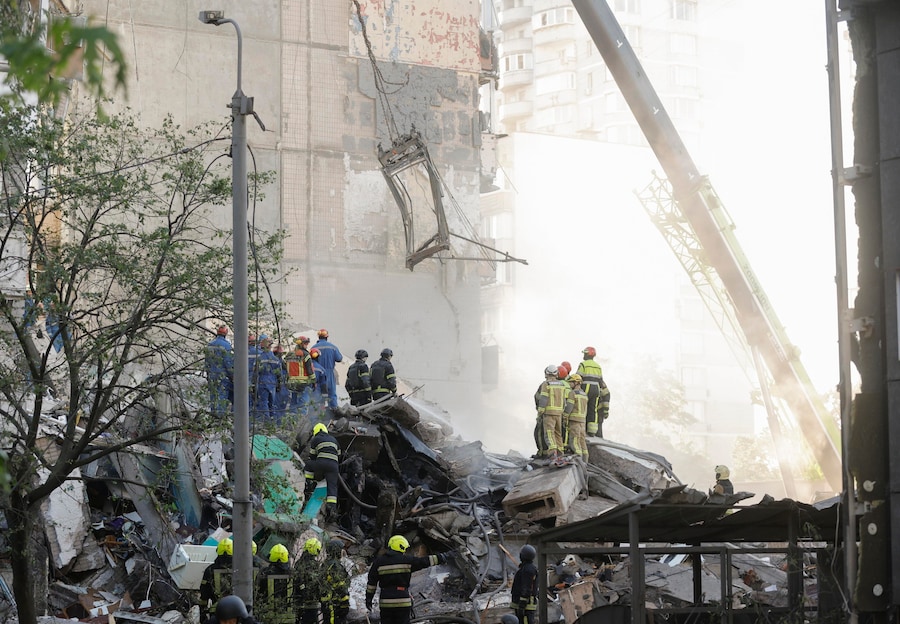 I soccorritori ucraini lavorano sul luogo di un attacco russo contro un edificio residenziale di nove piani a Kiev (EPA)