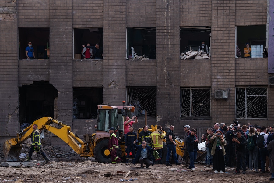 La gente guarda attraverso le finestre di un edificio danneggiato in seguito a un attacco russo contro un quartiere residenziale di Kiev. (AP Photo/Evgeniy Maloletka/APN)