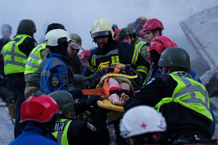 I soccorritori trasportano su una barella una donna ferita da un'abitazione gravemente danneggiata in seguito a un attacco russo contro un quartiere residenziale di Kiev. (AP Photo/Evgeniy Maloletka/APN)
