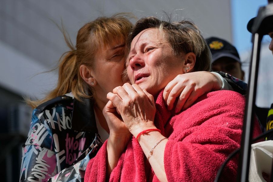 Una vicina abbraccia una donna in lacrime sul luogo di un attacco missilistico russo contro un edificio residenziale a Kiev. (AP Photo/Efrem Lukatsky/APN)