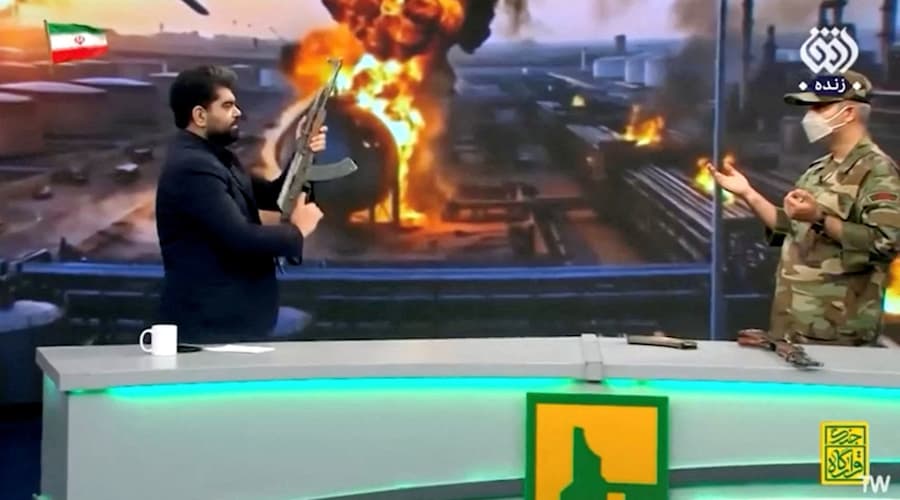 Un conduttore della TV di Stato iraniana e un istruttore di tiro dal vivo parlano in uno studio dove il conduttore ha sparato con una pistola contro una bandiera degli Emirati Arabi Uniti, a Teheran, il 15 maggio 2026. Foto Pool via WANA (West Asia News Agency)/via REUTERS (via REUTERS)