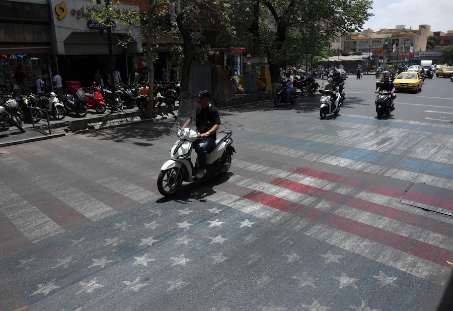 Alcuni iraniani passano in auto davanti a un dipinto raffigurante le bandiere degli Stati Uniti e di Israele in una strada di Teheran, in Iran, il 17 maggio 2026. Il conflitto tra l'Iran e gli Stati Uniti continua, mentre il presidente americano Donald Trump ha ribadito le minacce di una nuova azione militare contro l'Iran. EPA/ABEDIN TAHERKENAREH (EPA)