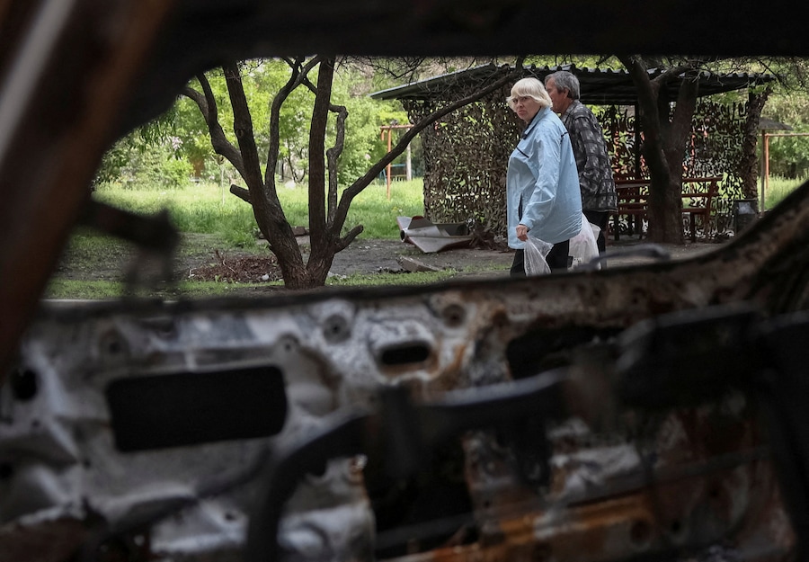 Alcuni residenti camminano vicino a un'auto distrutta, nel contesto dell'attacco russo all'Ucraina, nella città di Druzhkivka, in prima linea nella regione di Donetsk. (REUTERS/Anatolii Stepanov)