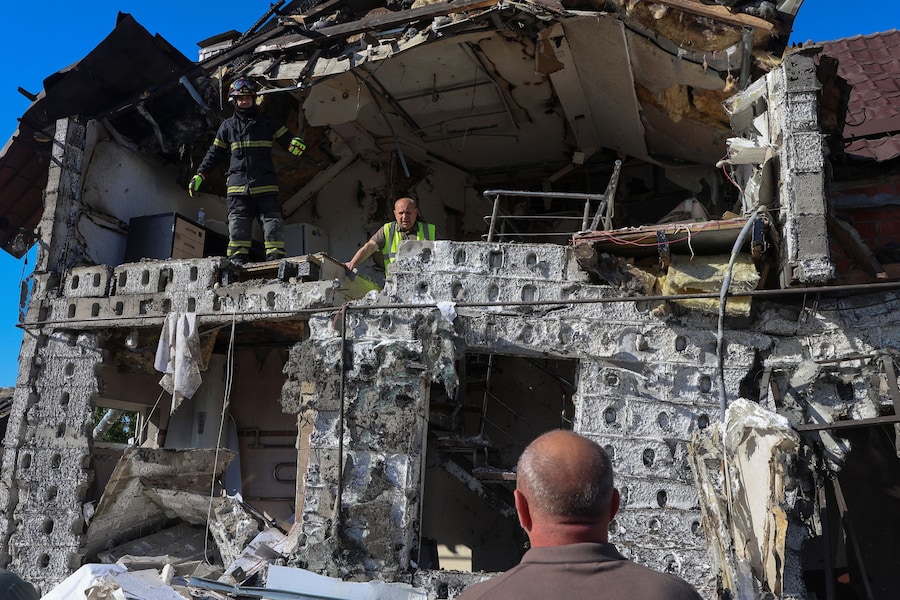 Residenti e un soccorritore ispezionano una casa colpita da un attacco con droni russi avvenuto in mattinata, nel contesto dell'offensiva russa contro l'Ucraina, a Kharkiv, Ucraina, il 19 maggio 2026. (REUTERS/Vyacheslav Madiyevskyy)
