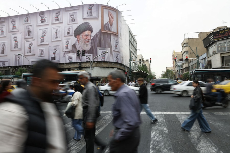Persone che camminano vicino a un cartellone pubblicitario con l'immagine del defunto leader supremo iraniano, l'ayatollah Ali Khamenei, a Teheran, in Iran, il 19 maggio 2026. Majid Asgaripour/WANA (West Asia News Agency) via REUTERS (via REUTERS)
