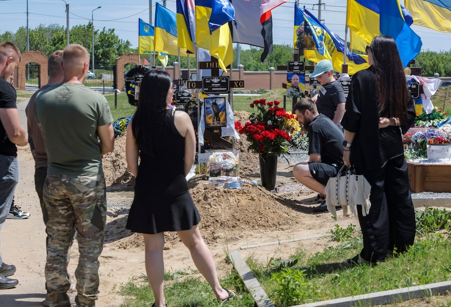 Un gruppo di persone in lutto si riunisce in segno di cordoglio presso le tombe degli agenti di polizia Igor Lisitsyn e Igor Radzyminsky, caduti in combattimento sul fronte, in un cimitero militare a Kharkiv, nell’Ucraina nord-orientale, il 20 maggio 2026, nel contesto dell’invasione russa. EPA/YEVHEN TITOV (EPA)