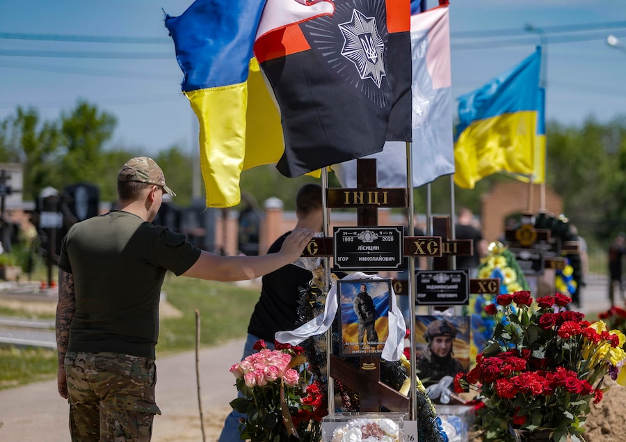 Un gruppo di persone in lutto si riunisce in segno di cordoglio presso le tombe degli agenti di polizia Igor Lisitsyn e Igor Radzyminsky, caduti in combattimento sul fronte, in un cimitero militare a Kharkiv, nell’Ucraina nord-orientale, il 20 maggio 2026, nel pieno dell’invasione russa. EPA/YEVHEN TITOV (EPA)