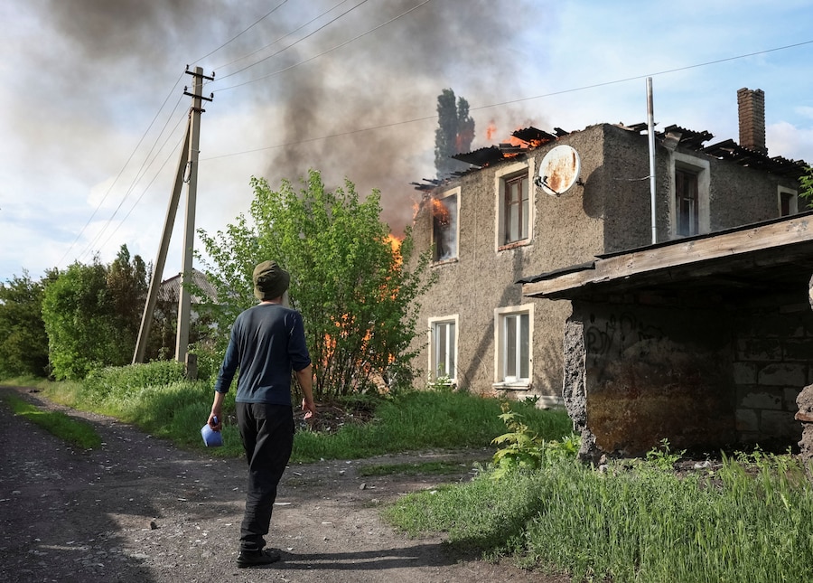 Un abitante si trova nei pressi di una casa in fiamme colpita da un drone russo, nel corso dell'attacco della Russia all'Ucraina, nella città di Bilozerske, in prima linea nella regione di Donetsk. (REUTERS/Anatolii Stepanov)