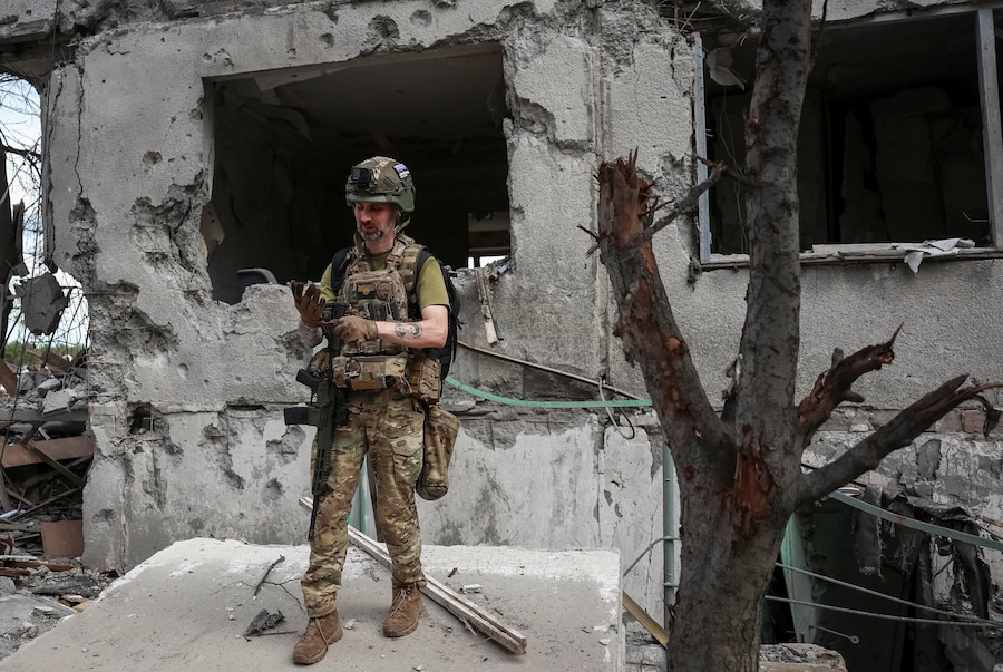 Un militare della divisione missili antiaerei della 15ª Brigata "Kara-Dag" dell'Assetto Operativo della Guardia Nazionale ucraina si trova nei pressi di un condominio distrutto, durante l'attacco russo all'Ucraina, nella città di Bilozerske, in prima linea nella regione di Donetsk. (REUTERS/Anatolii Stepanov)