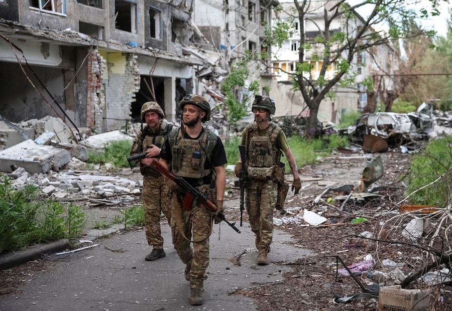 I militari della divisione missili antiaerei della 15ª Brigata "Kara-Dag" dell'Incarico Operativo della Guardia Nazionale ucraina camminano nei pressi di palazzi distrutti, durante l'attacco russo all'Ucraina, nella città di Bilozerske, in prima linea nella regione di Donetsk. (REUTERS/Anatolii Stepanov)