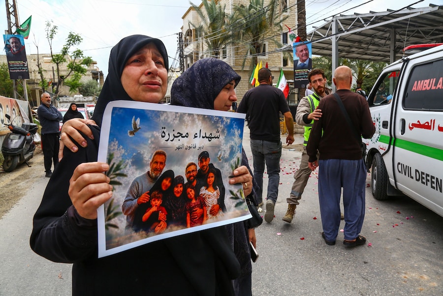 Un partecipante al funerale tiene in mano un cartello durante la cerimonia funebre in memoria delle vittime dell'attacco israeliano di martedì, a Deir Qanoun al-Nahr. (REUTERS)