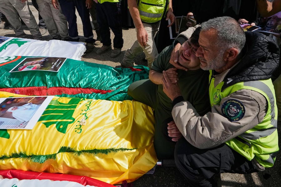 I parenti piangono sulle salme delle persone uccise martedì dai raid aerei israeliani nel villaggio meridionale di Deir Qanoun al-Nahr. (APN)
