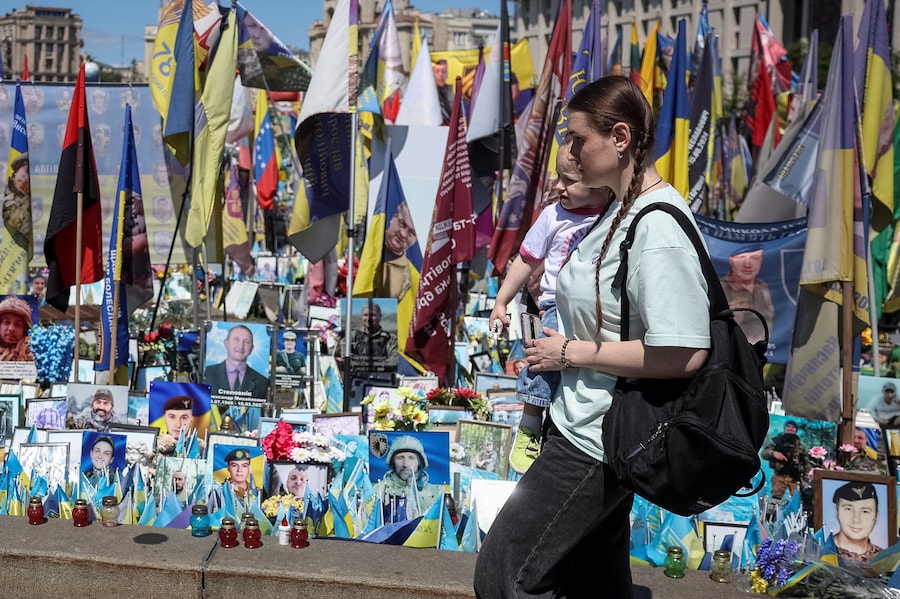 Una donna con un bambino visita un memoriale improvvisato dedicato ai militari caduti, mentre gli ucraini celebrano la Giornata degli Eroi, nel contesto dell'attacco russo all'Ucraina, a Kiev, Ucraina, il 23 maggio 2026. REUTERS/Gleb Garanich (REUTERS)